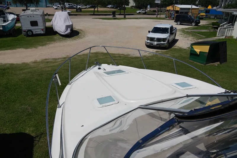 Slide: The Image of 2003 Bayliner Ciera 2855 boat parked on grass with vehicles in the background. - 7