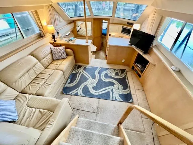 Slide: The Image of Interior of 1998 Carver 405 Motor Yacht with beige seating, TV, and nautical-themed decor. - 15