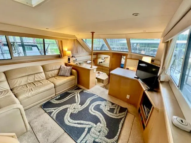 Slide: The Image of 1998 Carver 405 Motor Yacht interior with beige seating, nautical rug, and large windows. - 16