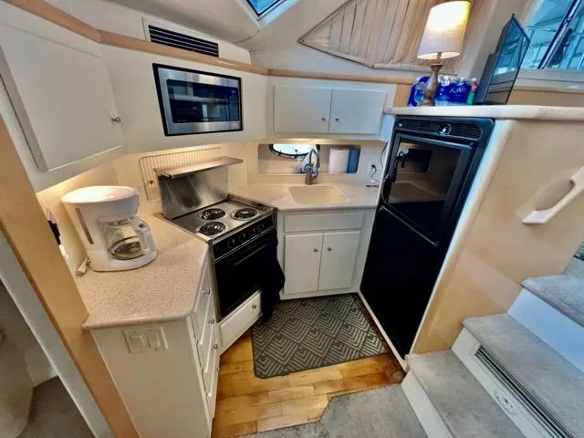 Slide: The Image of 1998 Carver 405 Motor Yacht kitchen with stove, microwave, and refrigerator. - 18