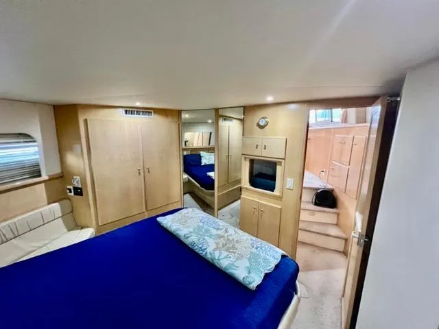 Slide: The Image of 1998 Carver 405 Motor Yacht interior with cozy bedroom, blue bedding, and wooden cabinetry. - 27