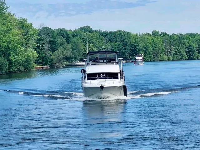 Slide: The Image of 1998 Carver 405 Motor Yacht cruising on a scenic river with lush green trees. - 3