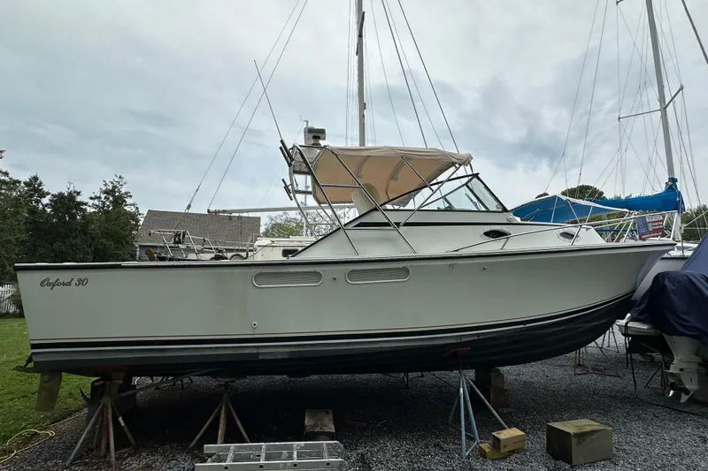 The Image of 1988 Black Watch 30 EXPRESS boat on stands, outdoor setting, overcast sky. - 0