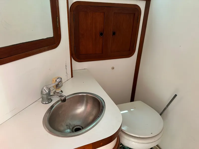 Slide: The Image of 1988 Black Watch 30 EXPRESS boat bathroom with sink, toilet, and wooden cabinet. - 10
