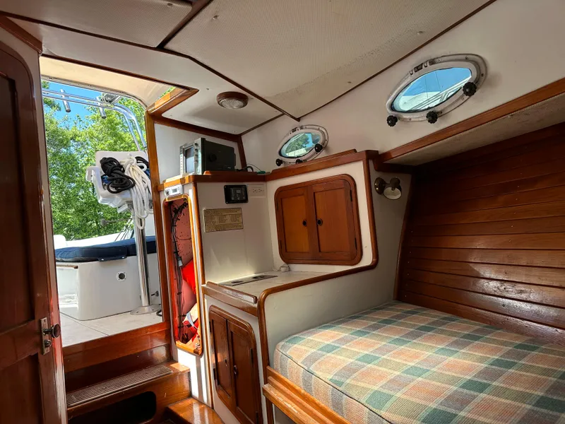 Slide: The Image of Interior of 1988 Black Watch 30 EXPRESS boat with wooden cabinetry and plaid bedding. - 11