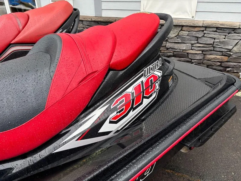 Slide: The Image of 2014 Kawasaki Jet Ski Ultra 310X with red and black seat, wet from rain. - 6