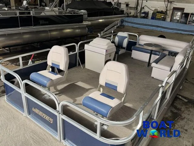 Slide: The Image of 2012 Weeres Cadet 200 Pontoon boat with blue and white seating, displayed indoors. - 18