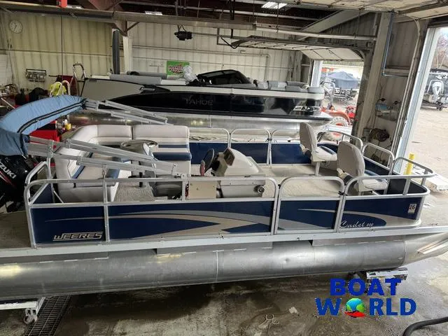 Slide: The Image of 2012 Weeres Cadet 200 Pontoon boat in a garage, featuring blue and white design. - 3