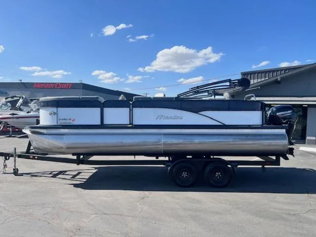 Slide: The Image of 2021 Manitou 23 Aurora LE VP pontoon boat on trailer under blue sky. - 1