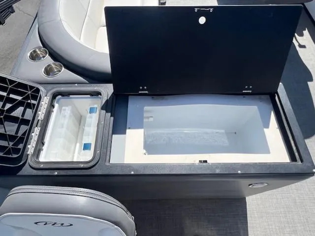 Slide: The Image of 2021 Manitou 23 Aurora LE VP boat storage compartment with open lid and cup holders. - 15
