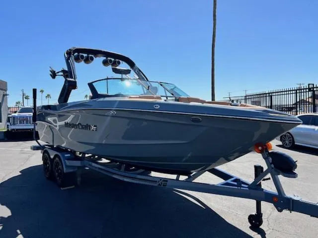 Slide: The Image of 2025 MasterCraft XT23 boat on trailer, sleek design, parked outdoors under clear sky. - 4