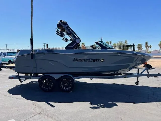 Slide: The Image of 2025 MasterCraft XT23 boat on trailer, parked outdoors under clear blue sky. - 5