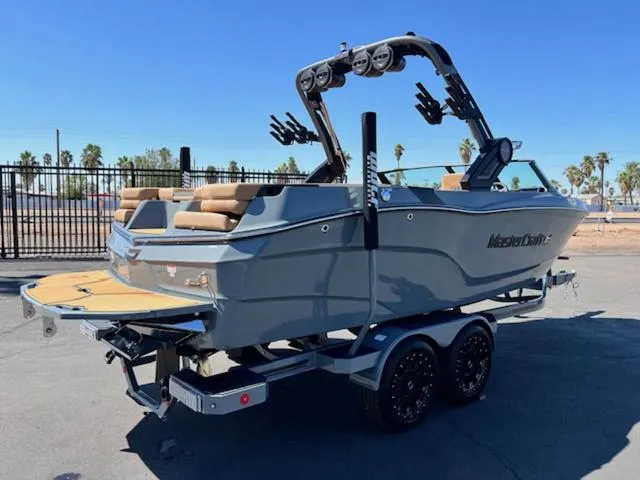 Slide: The Image of 2025 MasterCraft XT23 boat on trailer, gray exterior, parked outdoors. - 6
