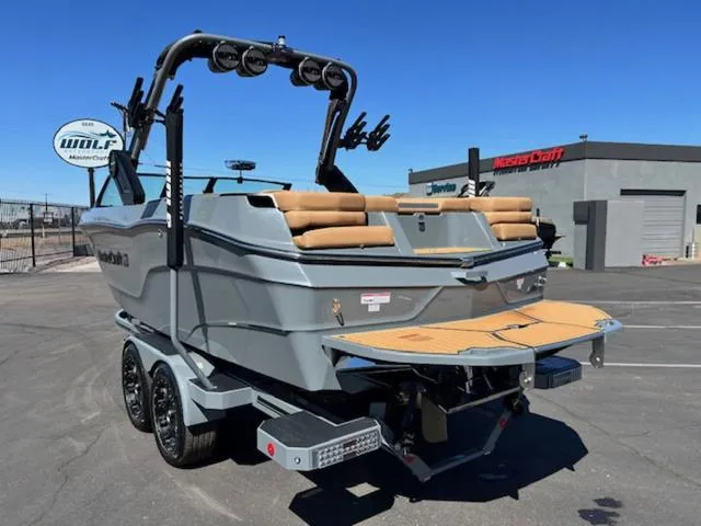 Slide: The Image of 2025 MasterCraft XT23 boat with sleek design and tan seating, parked outdoors. - 8