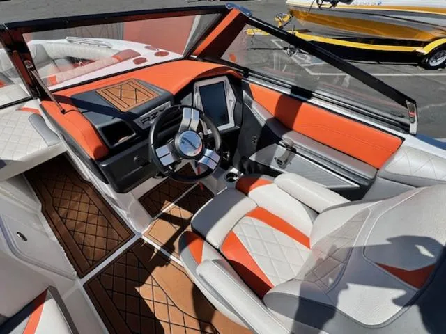 Slide: The Image of 2017 Tigé RZX2 boat interior with orange and white upholstery, modern dashboard, and steering wheel. - 11