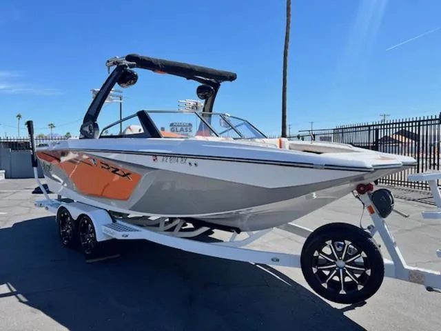 Slide: The Image of 2017 Tigé RZX2 boat on trailer, orange and white design, parked outdoors under clear blue sky. - 4