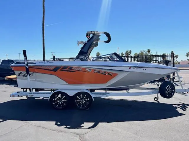 Slide: The Image of 2017 Tigé RZX2 boat on trailer, orange and white design, parked outdoors. - 5