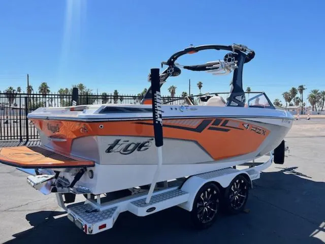 Slide: The Image of 2017 Tigé RZX2 boat with orange accents on a trailer, parked outdoors. - 6