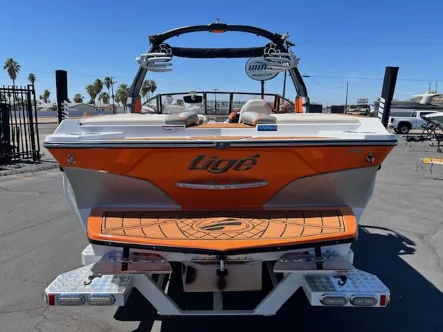 Slide: The Image of 2017 Tigé RZX2 boat, orange and white, rear view, parked outdoors. - 7
