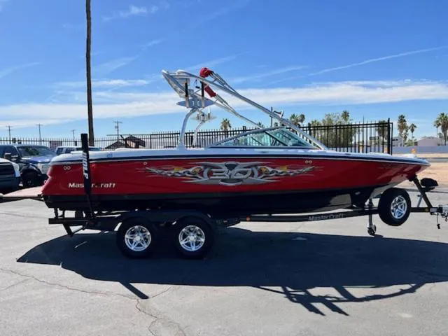 Slide: The Image of 2006 MasterCraft X30 boat with vibrant graphics on a trailer under clear blue skies. - 5