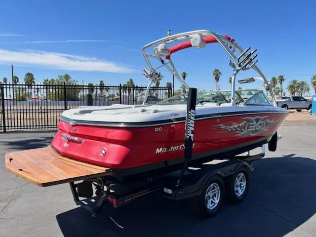 Slide: The Image of 2006 MasterCraft X30 boat on trailer, red with wakeboard tower, parked outdoors. - 6