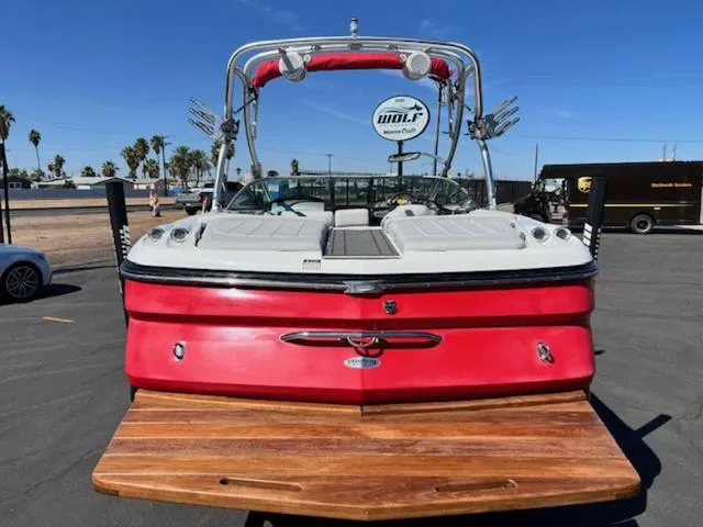 Slide: The Image of 2006 MasterCraft X30 boat with red exterior and wooden swim platform, parked outdoors. - 7