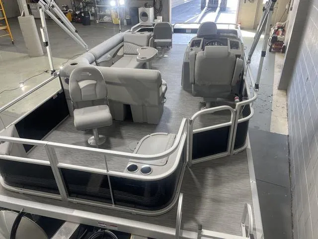 Slide: The Image of 2023 Bennington 20 SVF pontoon boat interior with seating and helm in a garage. - 8