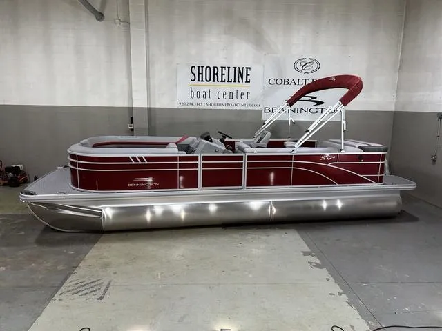Slide: The Image of 2023 Bennington 24 SXL pontoon boat in showroom, featuring sleek red design and modern amenities. - 1