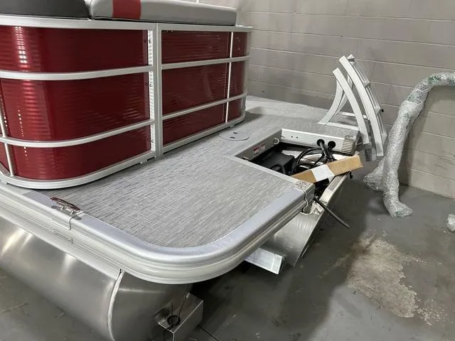 Slide: The Image of 2023 Bennington 24 SXL pontoon boat with red paneling and silver trim in a showroom. - 9