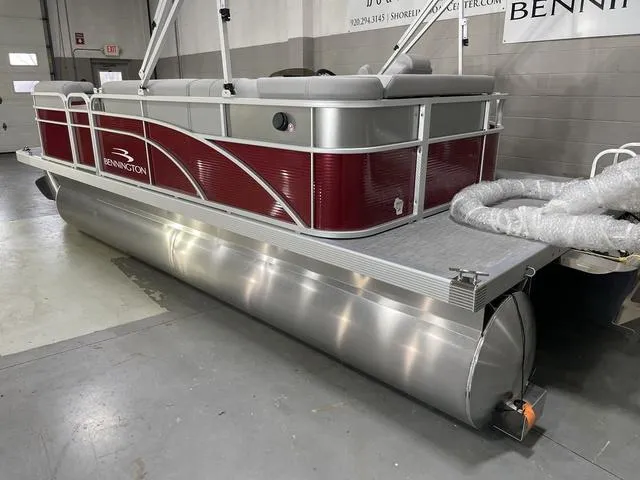 Slide: The Image of 2023 Bennington 20 SVL pontoon boat with red and silver design in a showroom. - 5