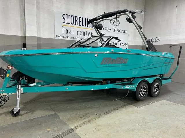 Slide: The Image of 2023 Malibu 21 LX boat in turquoise on a trailer at Shoreline Boat Center. - 1