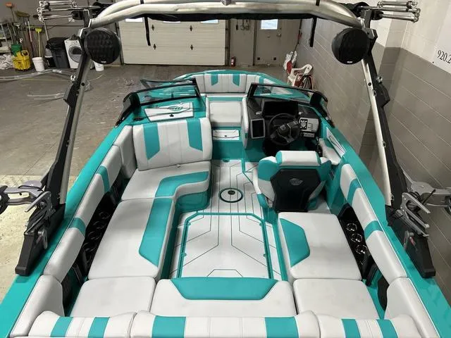 Slide: The Image of 2023 Malibu 21 LX boat interior with teal and white seating, modern dashboard, and spacious layout. - 12