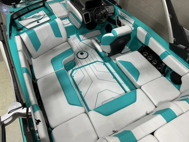 Slide: The Image of 2023 Malibu 21 LX boat interior with teal and white seating, modern dashboard, and spacious layout. - 13