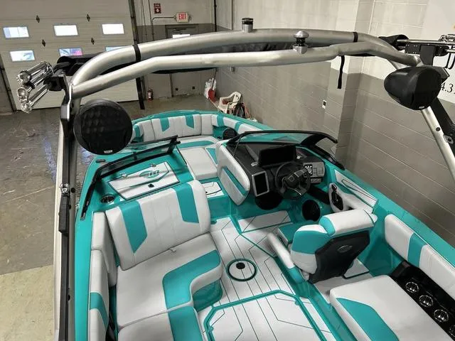 Slide: The Image of 2023 Malibu 21 LX boat interior with teal and white seating, modern dashboard, and wakeboard tower. - 14