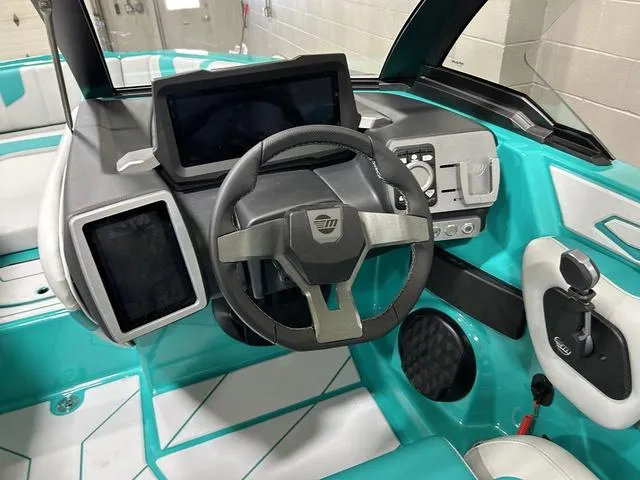 Slide: The Image of 2023 Malibu 21 LX boat dashboard with modern controls and teal interior accents. - 17