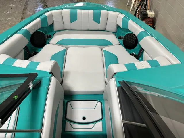 Slide: The Image of 2023 Malibu 21 LX boat interior with teal and white seating, featuring spacious layout and speakers. - 20