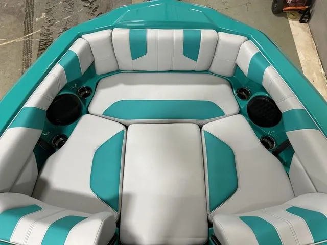 Slide: The Image of 2023 Malibu 21 LX boat interior with teal and white cushioned seating. - 21