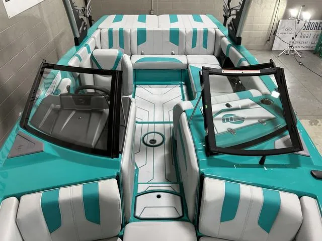 Slide: The Image of 2023 Malibu 21 LX boat interior with teal and white seating, modern design, and dual windshields. - 22