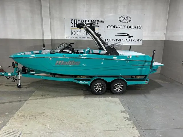Slide: The Image of 2023 Malibu 21 LX boat in showroom, turquoise color, on a trailer. - 4