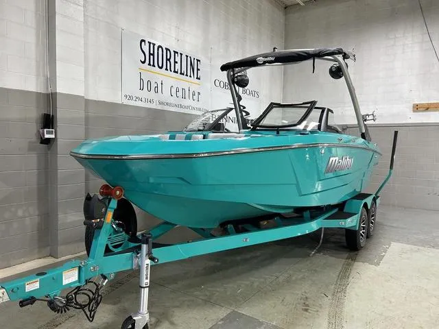 Slide: The Image of 2023 Malibu 21 LX boat in showroom, teal color, on trailer at Shoreline Boat Center. - 6