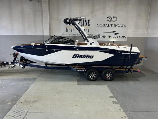 Slide: The Image of 2024 Malibu 23 LSV boat on trailer in showroom, featuring sleek design and modern features. - 1