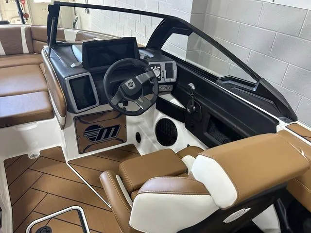 Slide: The Image of 2024 Malibu 23 LSV boat interior with modern dashboard and brown seating. - 16