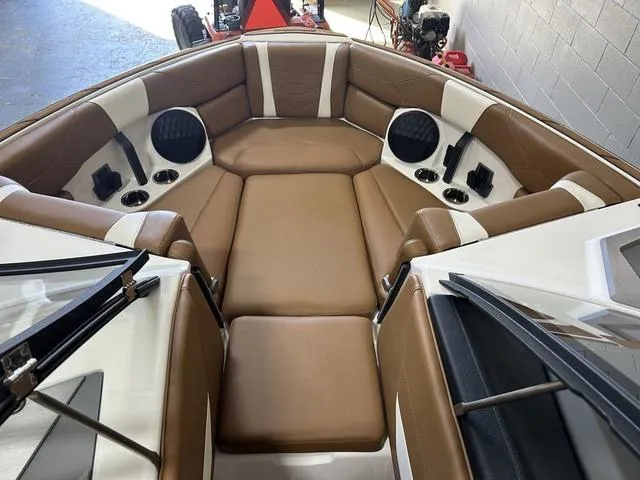 Slide: The Image of 2024 Malibu 23 LSV boat interior with brown and white seating, cup holders, and speakers. - 25