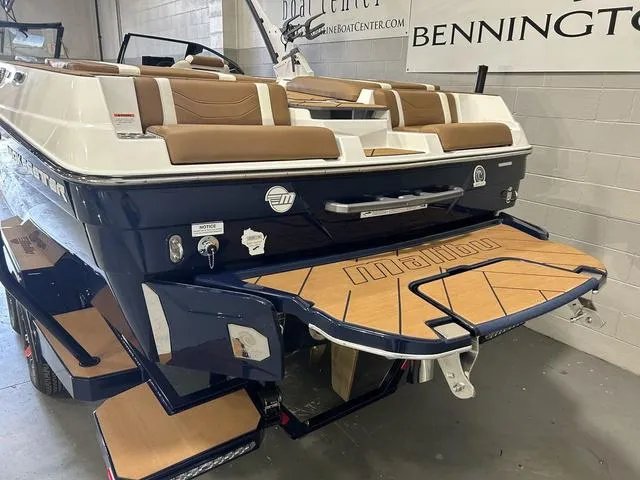 Slide: The Image of 2024 Malibu 23 LSV boat with tan seating and blue exterior in showroom. - 4