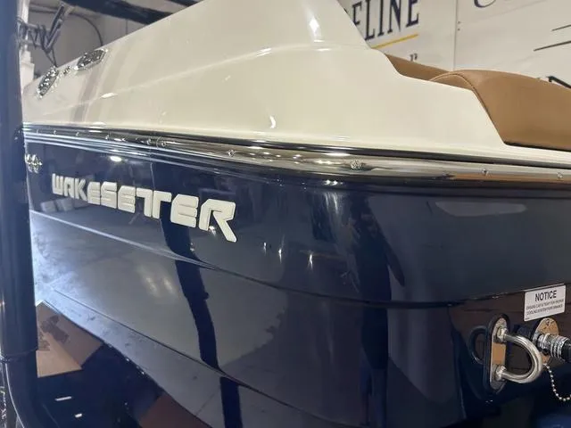 Slide: The Image of 2024 Malibu 23 LSV Wakesetter boat, blue and white exterior, in a showroom setting. - 5