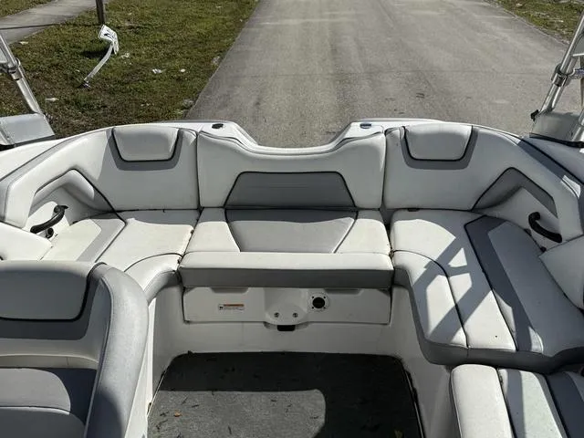 Slide: The Image of 2017 Yamaha Boats AR190 interior with white and gray seating, parked on a road. - 5