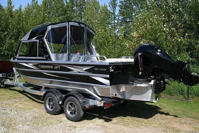 Slide: The Image of 2025 Thunder Jet 200 Luxor boat on trailer, parked outdoors with trees in background. - 3