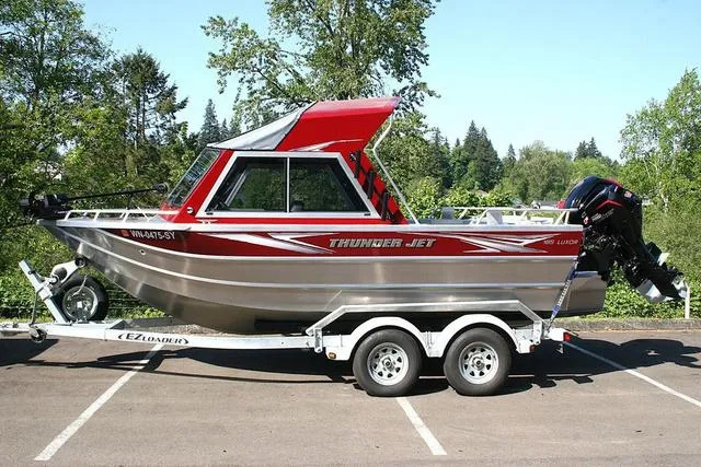 Slide: The Image of 2021 Thunder Jet 185 Luxor boat on trailer, parked outdoors with trees in background. - 2