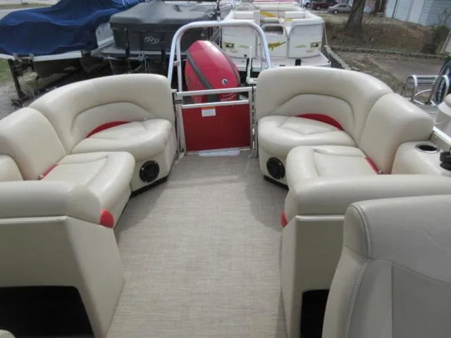 Slide: The Image of 2017 Landau 230C Atlantis Cruise Tritoon with beige seating and red accents, docked outdoors. - 13