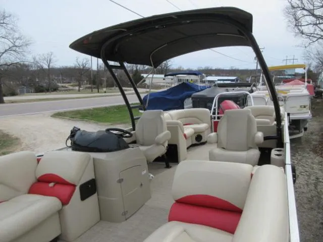 Slide: The Image of 2017 Landau 230C Atlantis Cruise Tritoon with beige and red seating, parked near a road. - 15